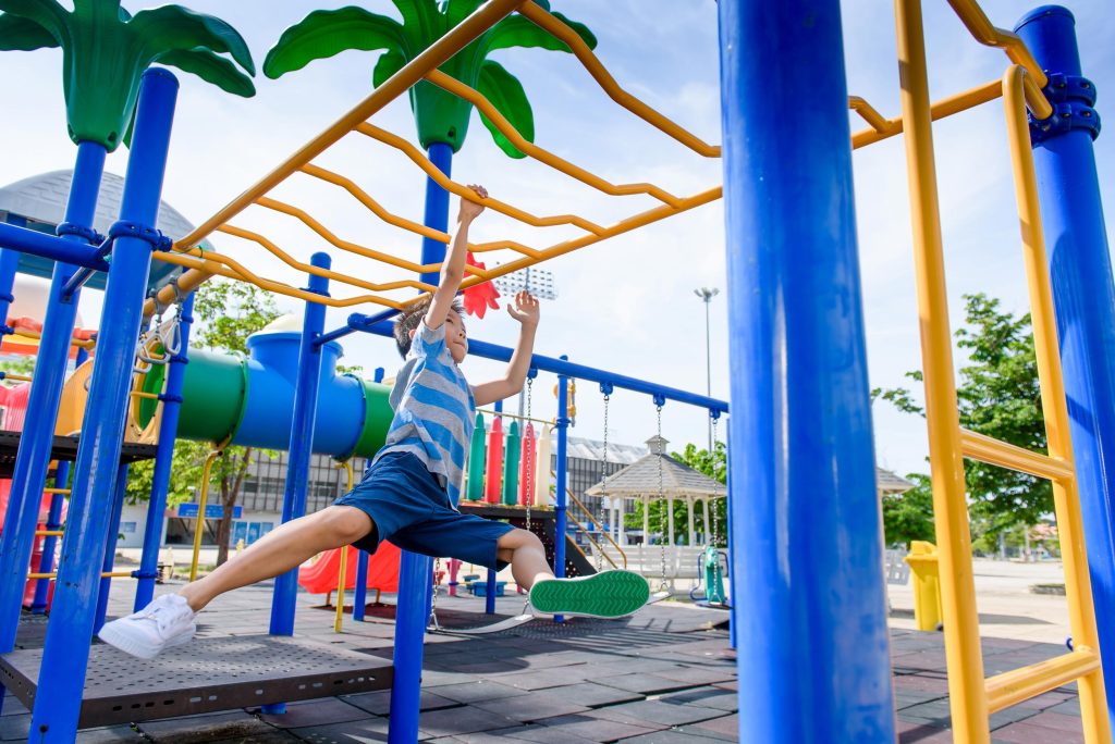 Menino brincando em playground ao ar livre, simbolizando lazer infantil e infraestrutura de condomínio.